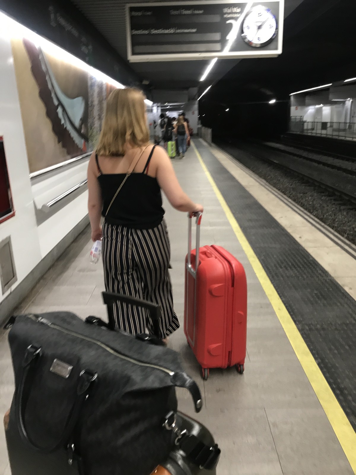 Henkilö matkalaukkujen kanssa metrotunnelissa.