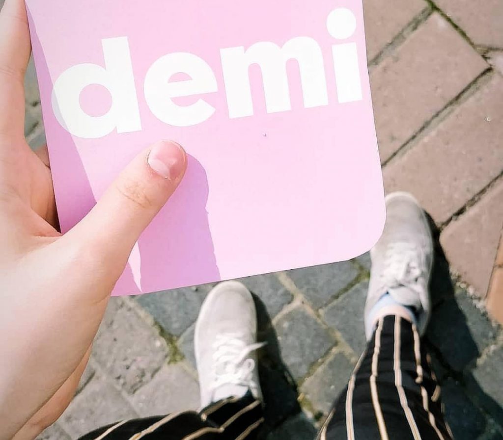 Henkilä pitelee korttia, jossa lukee Demi.