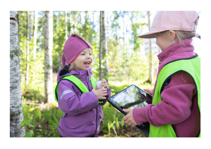 Kaksi lasta ottavat metsässä valokuvia tabletilla.