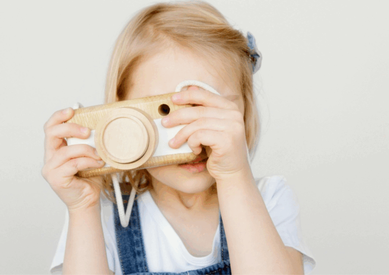 Lapsi, joka leikkii puisella kameralla.